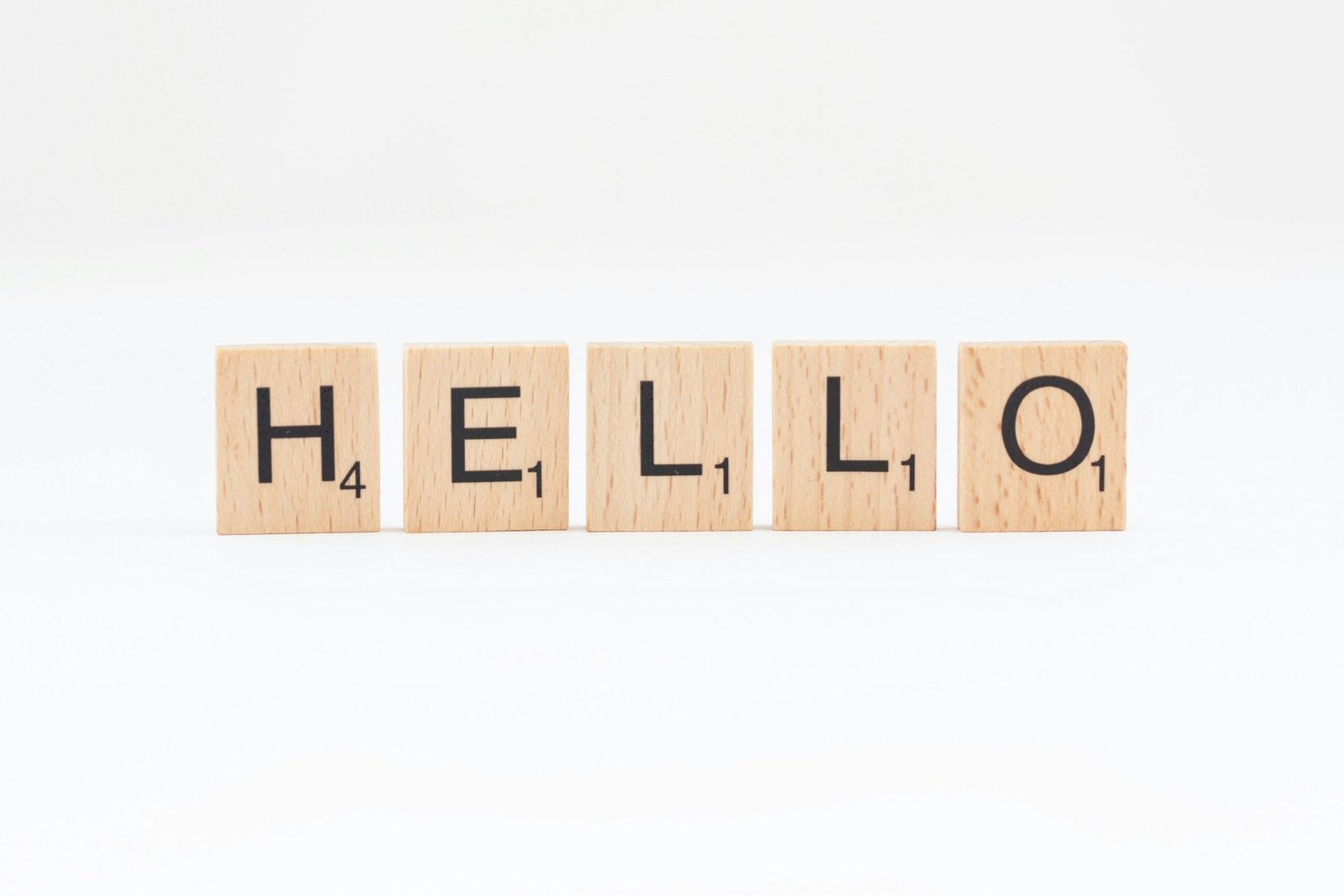 The word 'HELLO' in wooden letter tiles set against a white background.